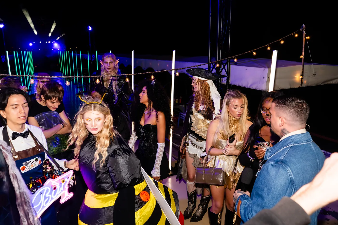 Gäste in Halloween-Kostümen feiern auf dem beleuchteten Schiffsdeck